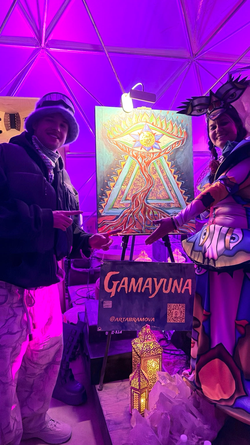 Gamayuna beside her painting at Playa Alchemist Bazaar, Burning Man 2026